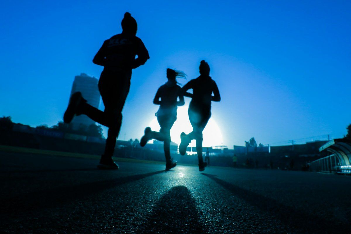 Trois coureuses en silhouette à contre-jour sur une route