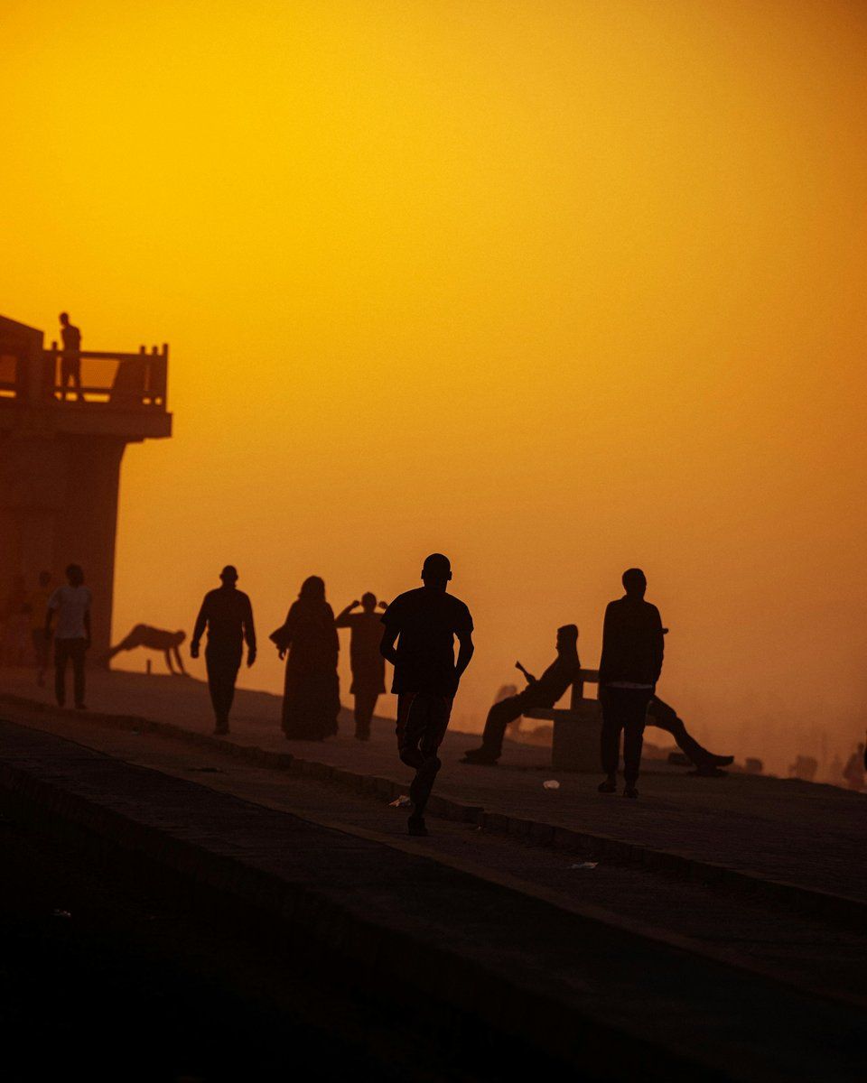Silhouettes marchant et courant au coucher du soleil, à Yoff, au nord de Dakar