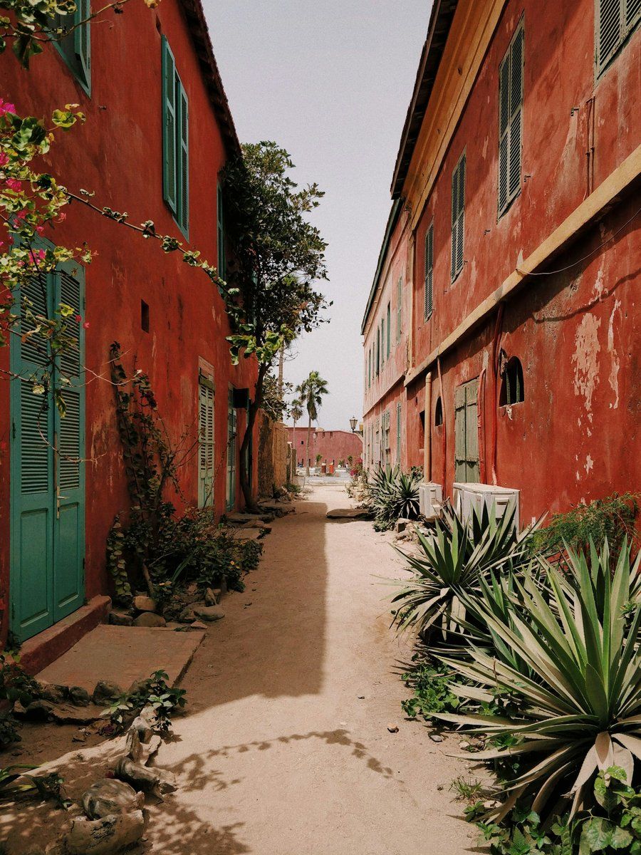 Ruelle sableuse entre des maisons aux murs rouges sur l'île de Gorée, à Dakar