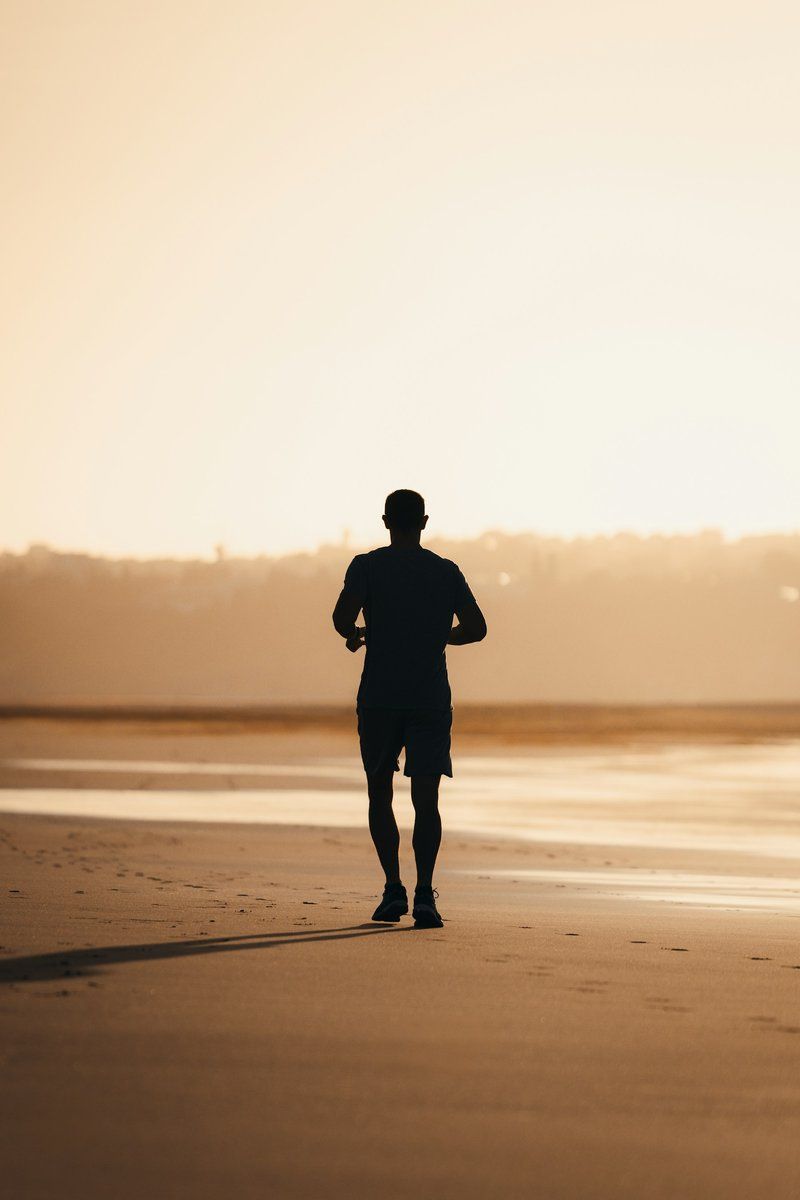 Silhouette d'un coureur sur une plage au soleil couchant