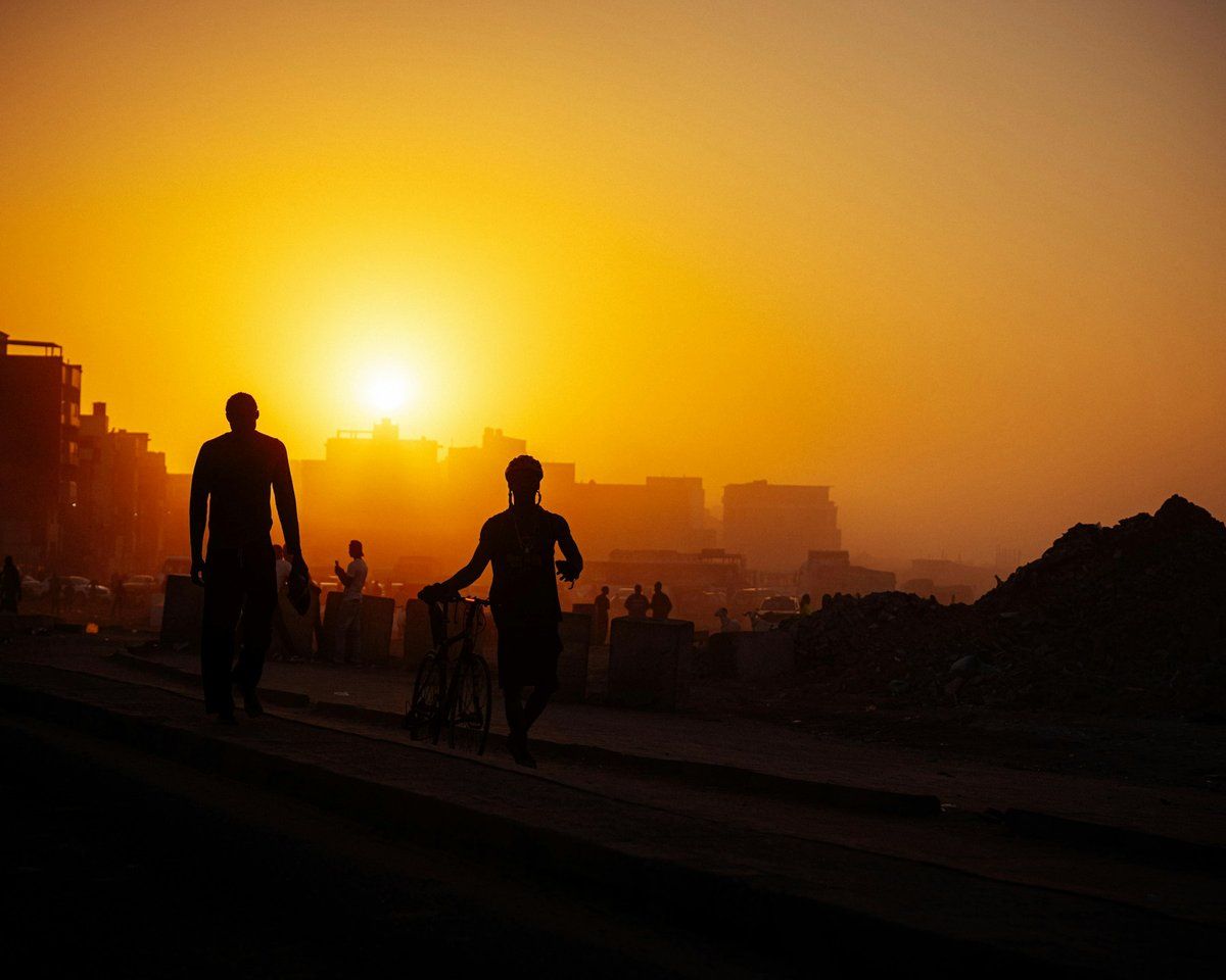 Silhouettes de promeneurs et de coureurs au coucher du soleil sur le littoral de Yoff, à Dakar